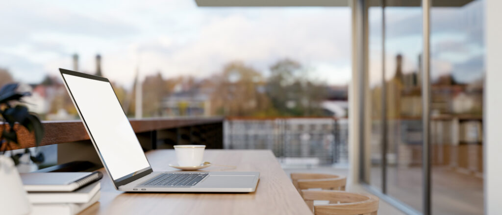 Ordinateur portable posé sur un bureau lumineux avec carnet et tasse de café, évoquant un espace de travail calme pour la rédaction web, la correction et la relecture.